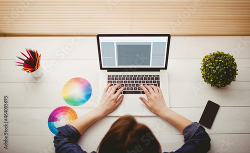 Hands of caucasian female programmer with colour charts using laptop with coding on screen