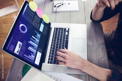 Hands of caucasian businessman sitting at desk, using laptop with statistical data on screen photo