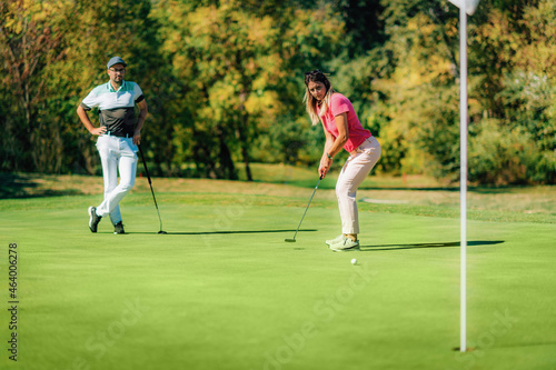 Golfing couple, putting on the green, beautiful weather