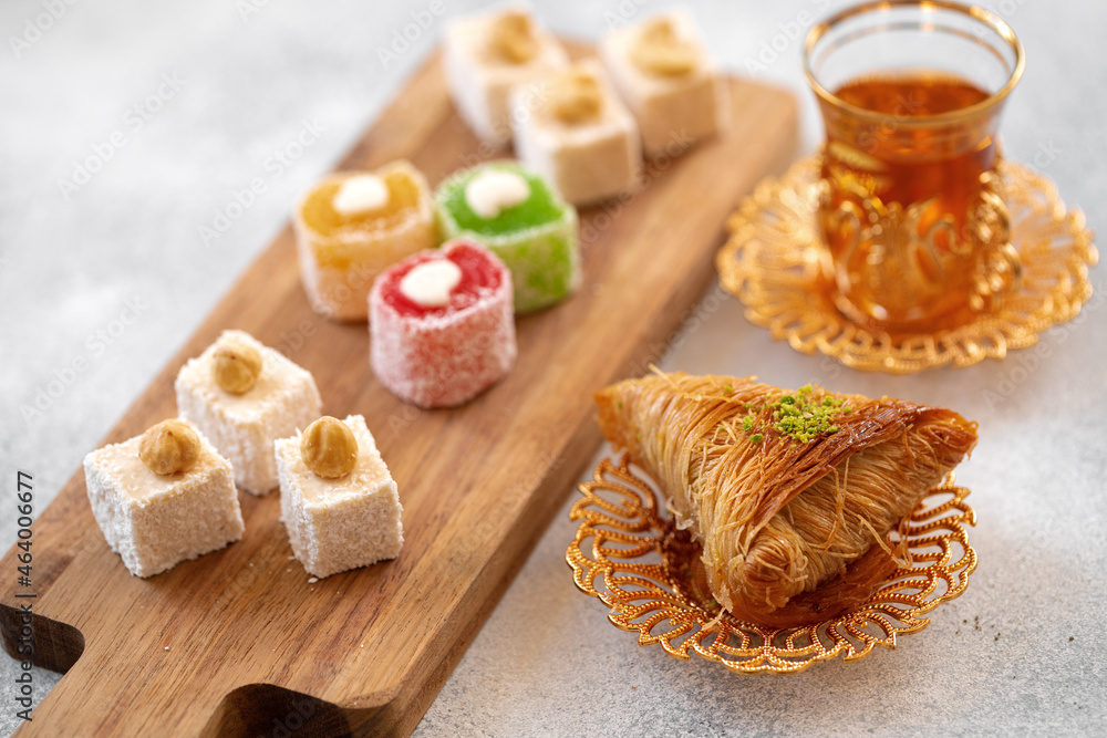 Various Turkish sweets and cup of tea on white textured background