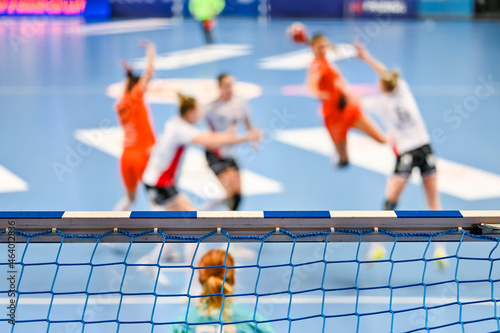 Detail of handball goal crossbar with net and women handball match in the background. photo