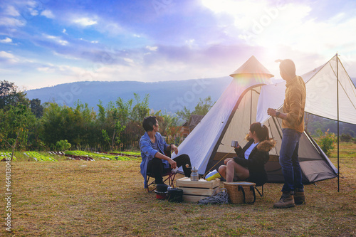 Happiness friends have good time morning on camping trip with sunrise background. Traveler enjoy camping with morning coffee.	