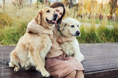 beautiful girl hugs two golden retrievers. Outdoor