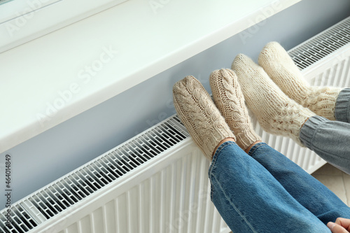 Foto Concept of heating season with legs in knitted boots on radiator