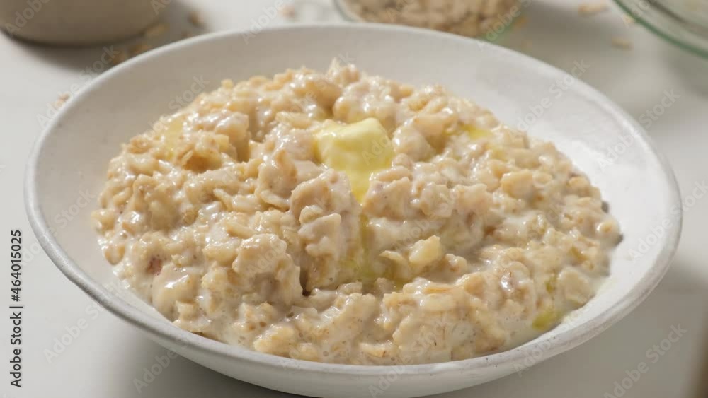 Stirring butter in the plate with oatmeal porridge with a spoon. Healthy breakfast. close up. 4k video Stirring butter in the plate with oatmeal porridge with a spoon. Healthy breakfast. close up. 4k video