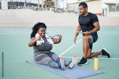 Curvy woman and personal trainer doing workout session outdoor - Main focus on girl face photo