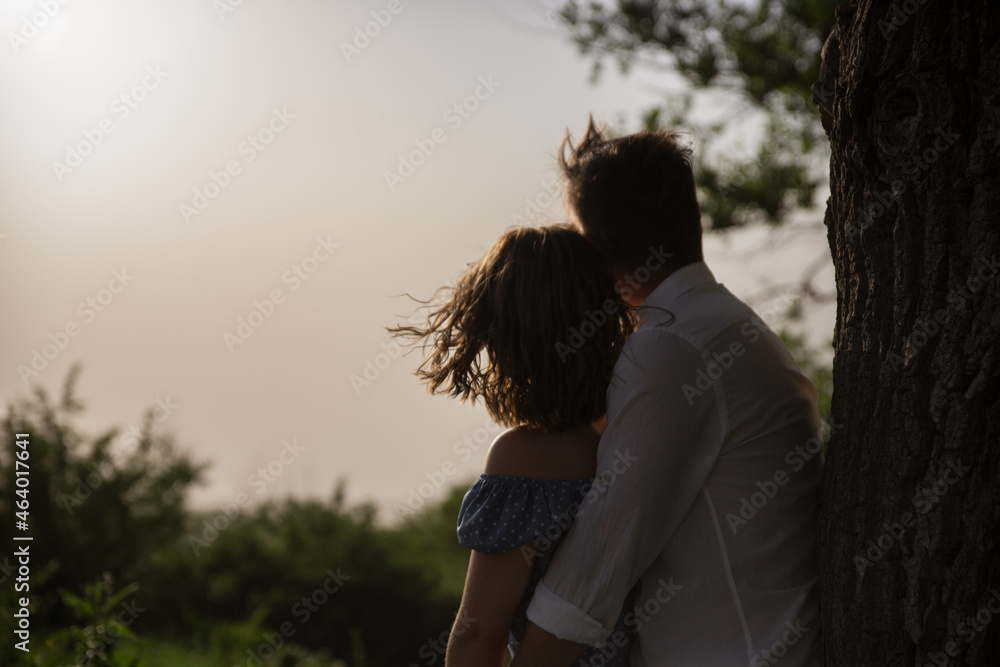 A couple hugs each other with love at a tree and look into the distance: into the sky and into the future A couple hugs each other with love at a tree and look into the distance: into the sky and into the future