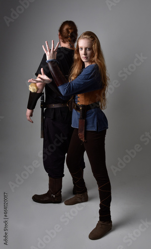 Full length portrait of red haired couple, man and woman wearing medieval viking inspired fantasy costumes, standing romantic intimate poses, isolated on white studio background.