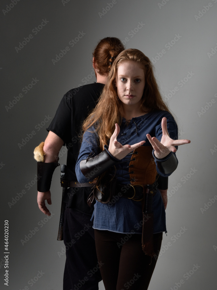 Full length portrait of red haired couple, man and woman wearing medieval viking inspired fantasy costumes, standing romantic intimate poses, isolated on white studio background. Full length portrait of red haired couple, man and woman wearing medieval viking inspired fantasy costumes, standing romantic intimate poses, isolated on white studio background.