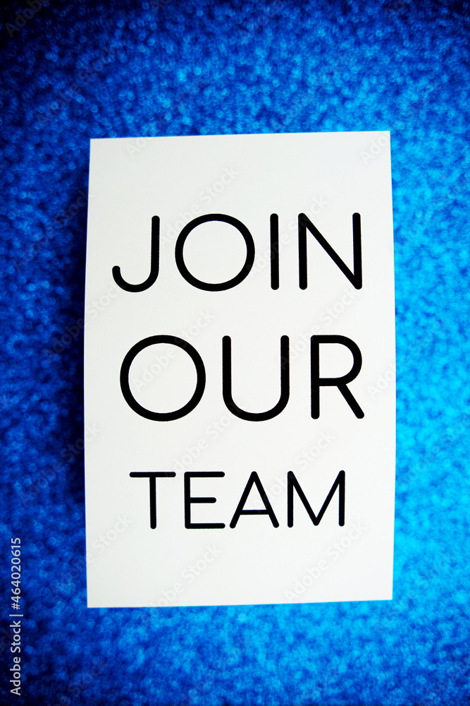 Join our team text on paper card top view on blue bokeh background Join our team text on paper card top view on blue bokeh background