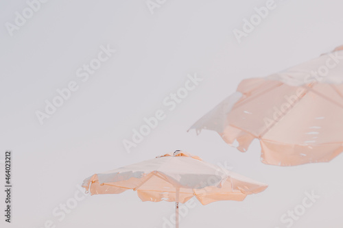 White beach patio sun umbrellas above white sky. Neutral color.