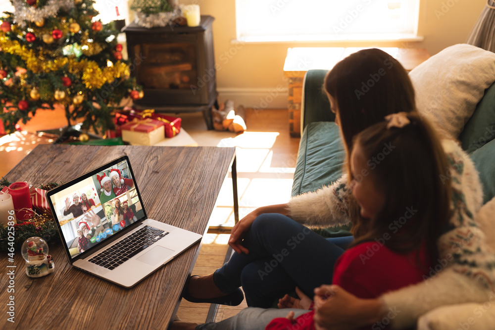 Fototapeta premium Caucasian mother and daughter on laptop christmas video call with smiling friends