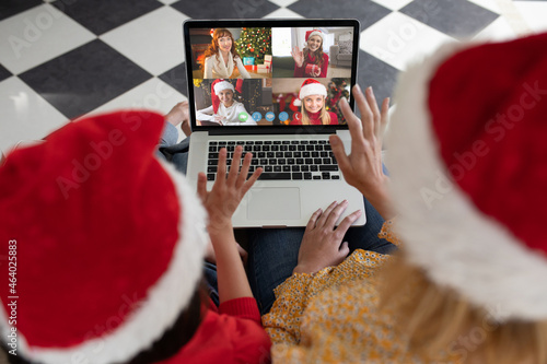 Caucasian mother and daughter in santa hats on laptop christmas video call with friends