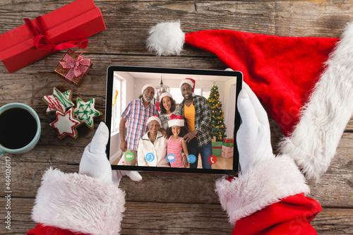 Santa claus holding tablet, making christmas video call with smiling african american family