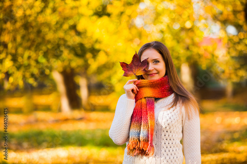 Woman in scarf hided with a maple leaf on fall background