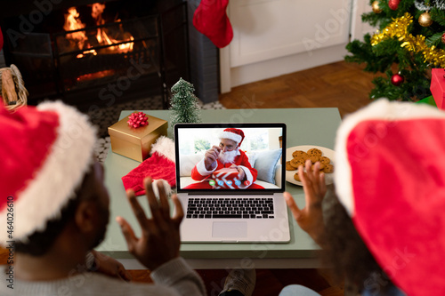 Waving african american couple making laptop christmas video call with senior man in santa costume © vectorfusionart