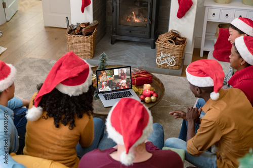 Diverse group of friends making laptop christmas video call with four smiling female friends photo