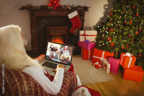 Caucasian santa claus on christmas laptop video call with diverse group of friends photo