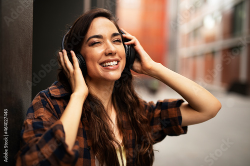 Young smiling woman with headphones outdoors. Beautiful happy girl listening the music