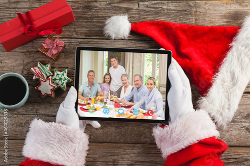 Hands of santa claus holding tablet with caucasian family on screen