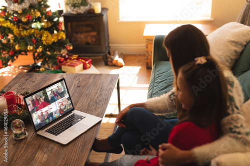 Caucasian mother and daughter on christmas video call on laptop with friends and family
