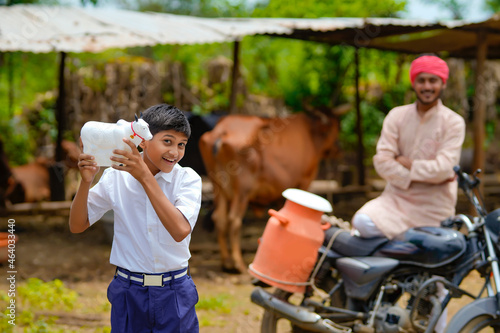 Indian school boy holding cow shape piggy bank in hand and standing with father
