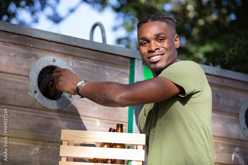 a mid-adult man recycling glass bottles photo