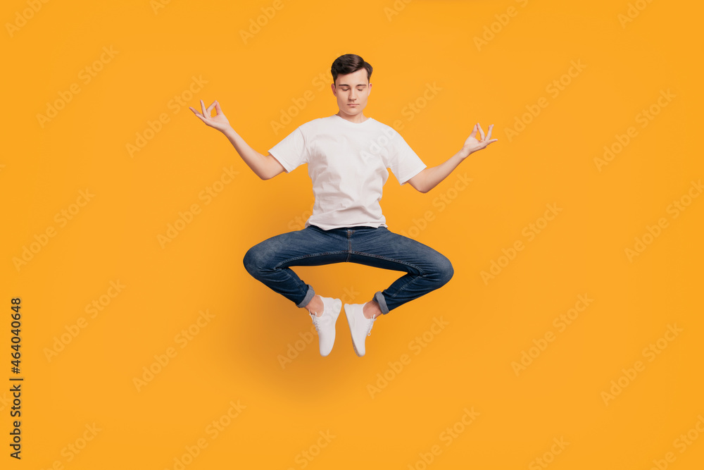 Portrait of funny peaceful dreamy guy jump meditate harmony concept on yellow background