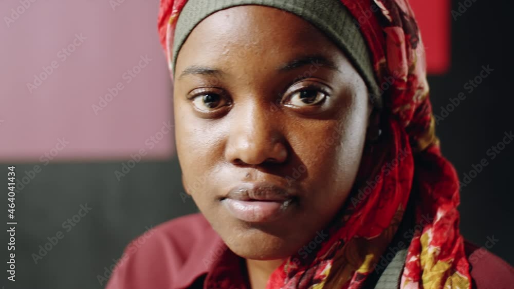 Close-up of young beautiful Black woman wearing colorful hijab, looking on camera, posing in studio Close-up of young beautiful Black woman wearing colorful hijab, looking on camera, posing in studio