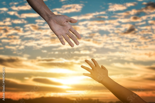 Giving a help hand concept. Reaching hand helping, hope and support each other over sunset background.