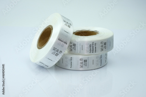 Skein tags for clothing, satin ribbon with symbols for the use of clothing. White skeins, a roll of ribbon with information on washing and fabric composition. Labels that are sewn to the inside