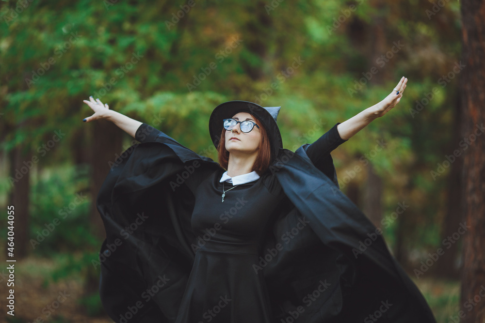 Halloween Witch. Portrait of a girl in a hat and a witch costume in the forest. Ready for trick or treat holiday