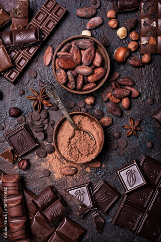 Chocolate background with lots of bars, nuts, cocoa beans and powder