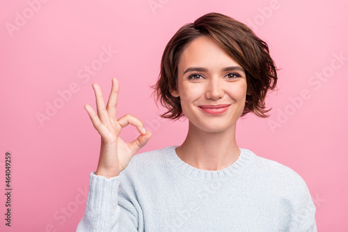 Photo of reliable positive lady show okey sign approve feedback wear blue sweater isolated pink color background photo
