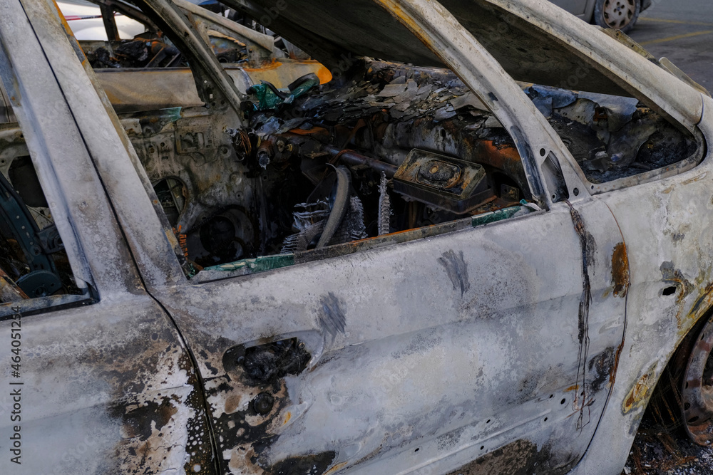 Burnt car's door in the street close-up. Riot, civil protest, hooliganism, criminal in the city. Explosion, fire result. Car insurance concept Burnt car's door in the street close-up. Riot, civil protest, hooliganism, criminal in the city. Explosion, fire result. Car insurance concept