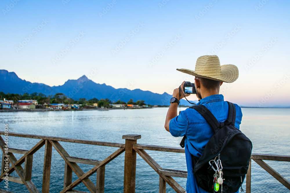 tourist taking a photograph at sunrise of the mountains and sea in the city of La Ceiba, Honduras. travel concept.
