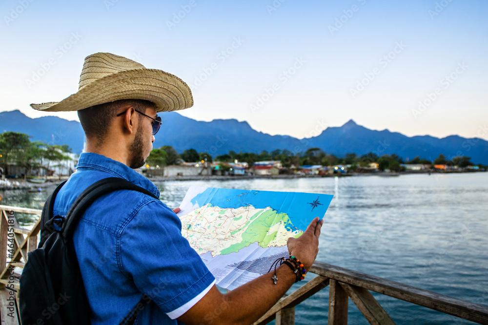 traveler man in front of the sea looking at a map of honduras. travel and tourism concept.