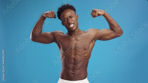 Basic instincts. Aggressive shirtless african american man flexing muscles and grinning, demonstrating his strength photo
