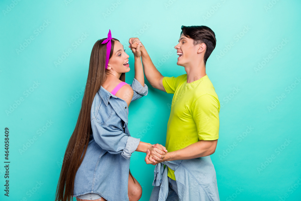 Profile photo of impressed brunette millennial couple dance wear yellow pink t-shirts isolated on teal color background Profile photo of impressed brunette millennial couple dance wear yellow pink t-shirts isolated on teal color background