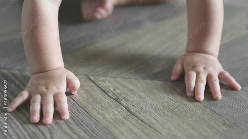 close-up tiny little hands fingers of caucasian baby infant touching beating crawling on the wooden floor at home. kid trying to move crawl first time palm and feet on the parquet living room daytime close-up tiny little hands fingers of caucasian baby infant touching beating crawling on the wooden floor at home. kid trying to move crawl first time palm and feet on the parquet living room daytime
