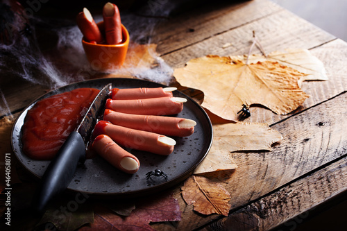 Sausages in tomato sauce for halloween on wooden autumn table, concept of scary food for the holiday, horizontal, place for text