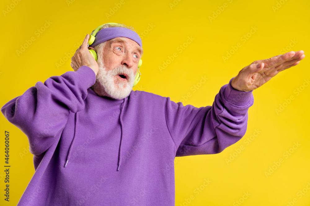 Low angle view photo of senior man enjoy rhythm music headphones dance party disco isolated over yellow color background Low angle view photo of senior man enjoy rhythm music headphones dance party disco isolated over yellow color background
