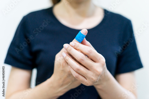 Quadro em tela Close up young woman puts a adhesive tape on her finger