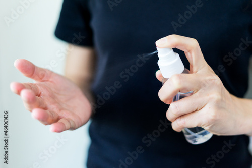 Cloes up woman in black t-shirt with alcohol based handwashing spray as a preventive hygiene measure against coronavirus infection. Antibacterial hand female sanitizer gel on white isolate background.