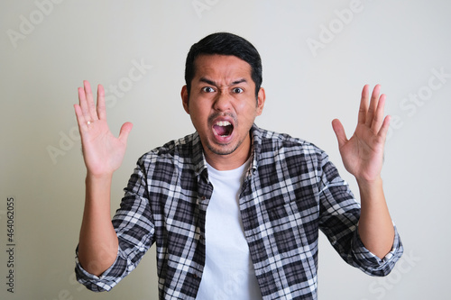 Adult Asian man screaming angry while looking forward photo