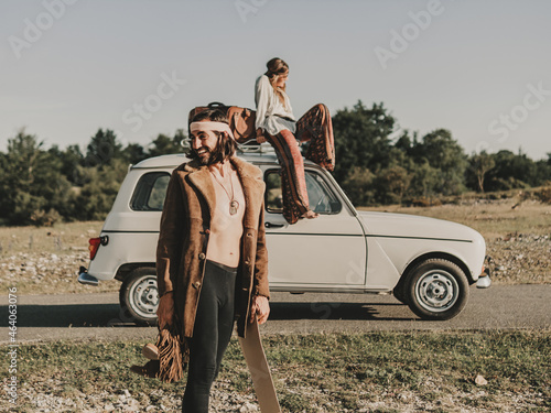 Positive hippie couple in nature with retro car photo