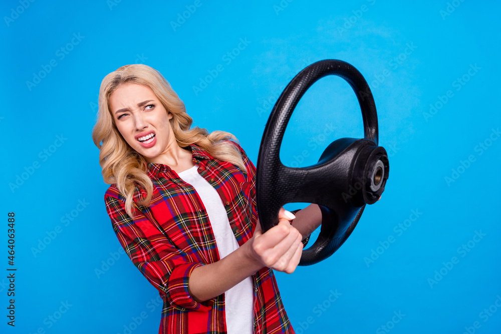 Photo of upset shocked young lady wear plaid shirt holding steering wheel looking empty space isolated blue color background Photo of upset shocked young lady wear plaid shirt holding steering wheel looking empty space isolated blue color background