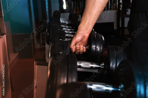 A man's hand takes a sports dumbbell. 