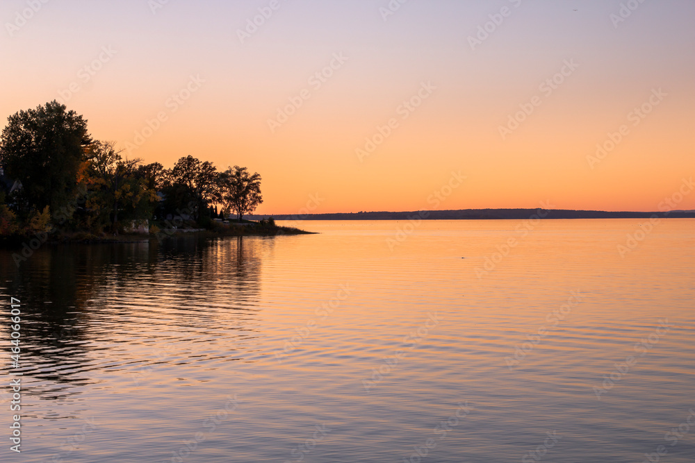 Beautiful sunset sky with trees and land jutting into the water