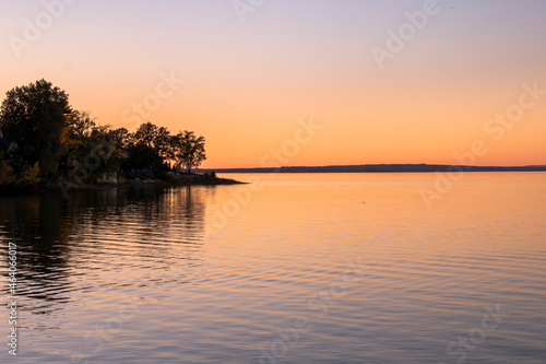 Beautiful sunset sky with trees and land jutting into the water